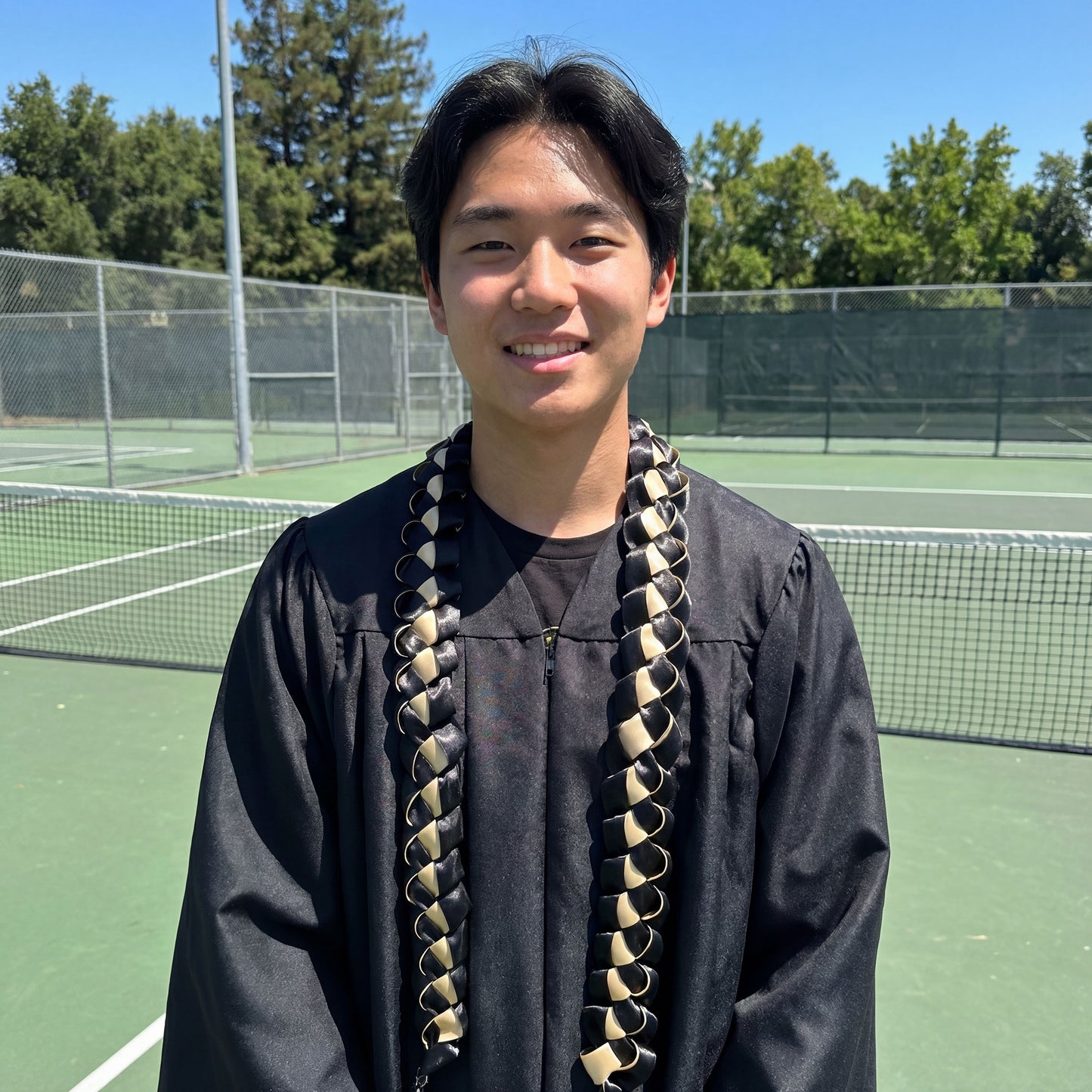 Male high school graduate wearing a black and gold custom graduation lei.