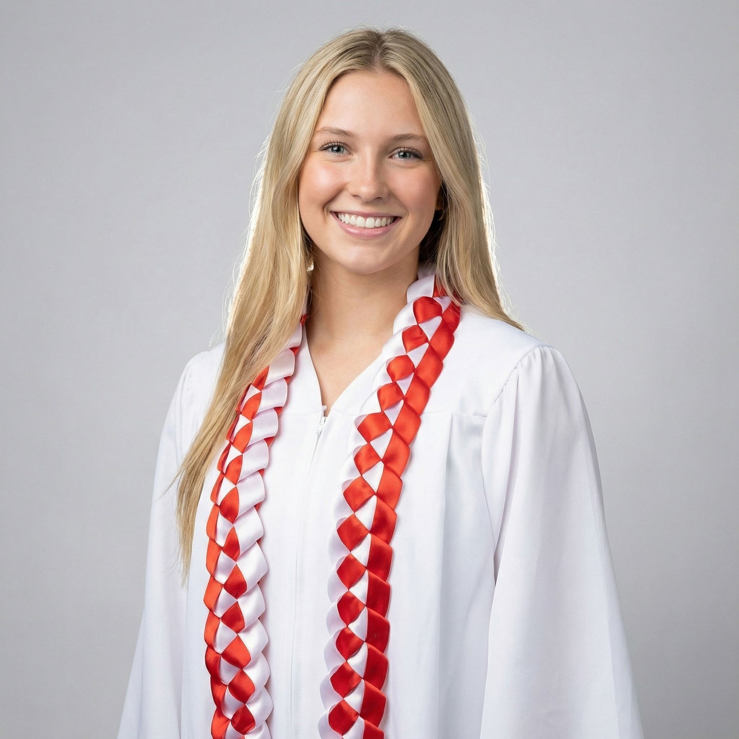 Female graduate smiling in a white gown wearing a handcrafted red and white single military braid satin ribbon lei during a professional senior portrait session.