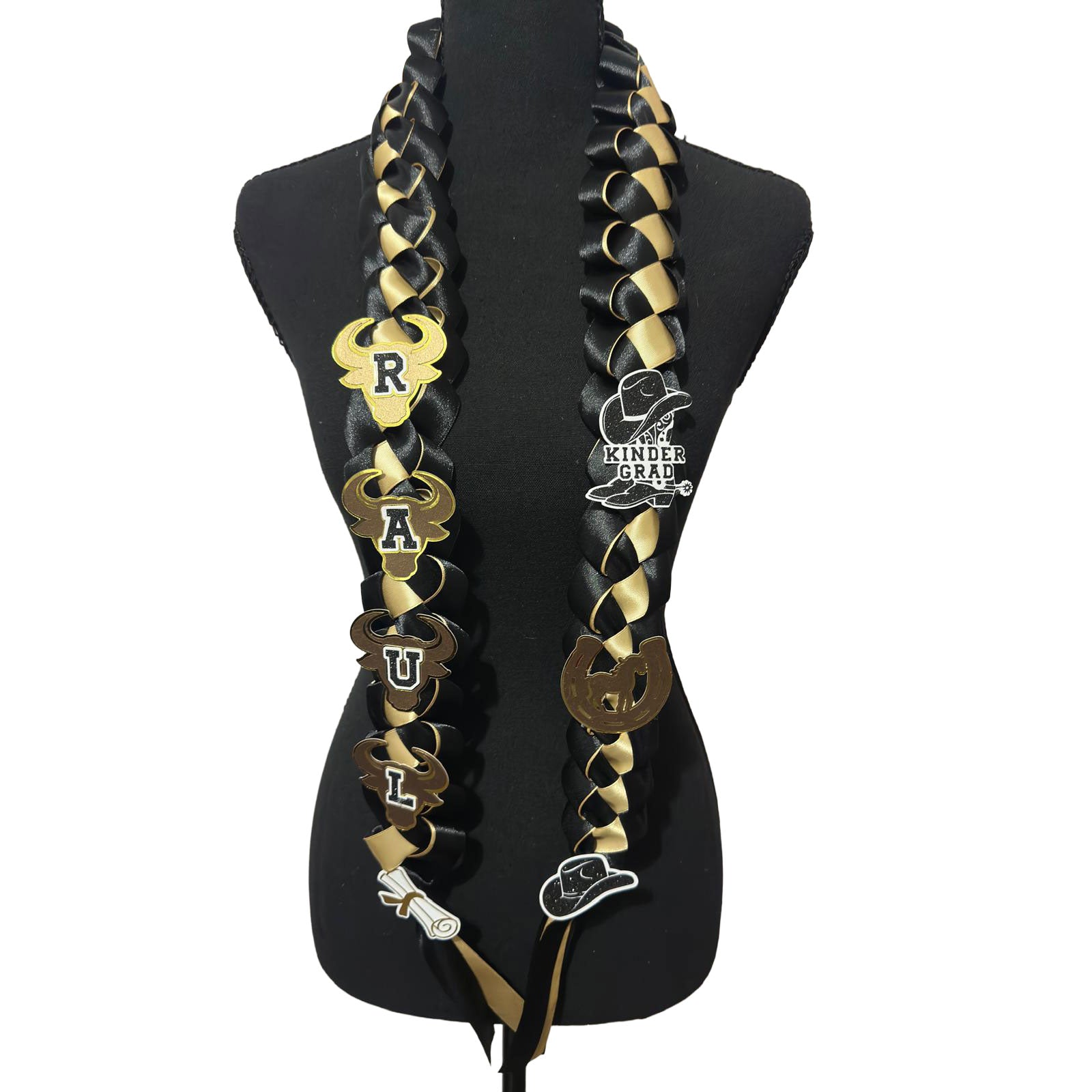 Front view of a custom black and gold braided satin ribbon graduation lei on a black mannequin display, featuring western cowboy theme cutouts and satin streamers.