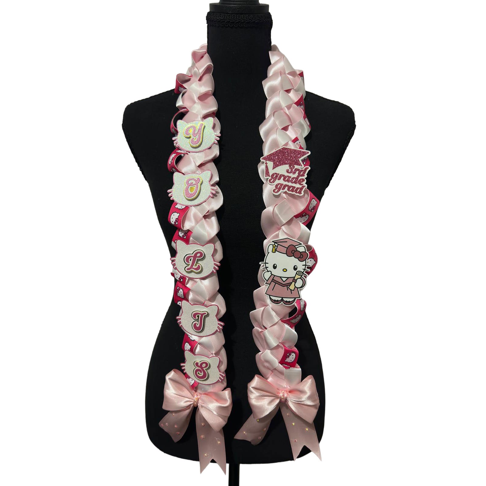 Front view of a custom pink and white braided satin ribbon graduation lei on a black mannequin display, featuring personalized lettering and oversized satin bows with rhinestones.