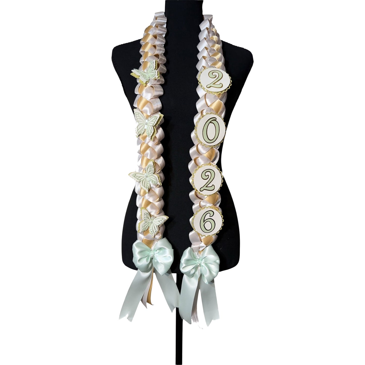 Front view of a 2026 graduation lei featuring a mint green, gold, and white single military braid design with layered mint butterfly accents and year charms on a black display mannequin.