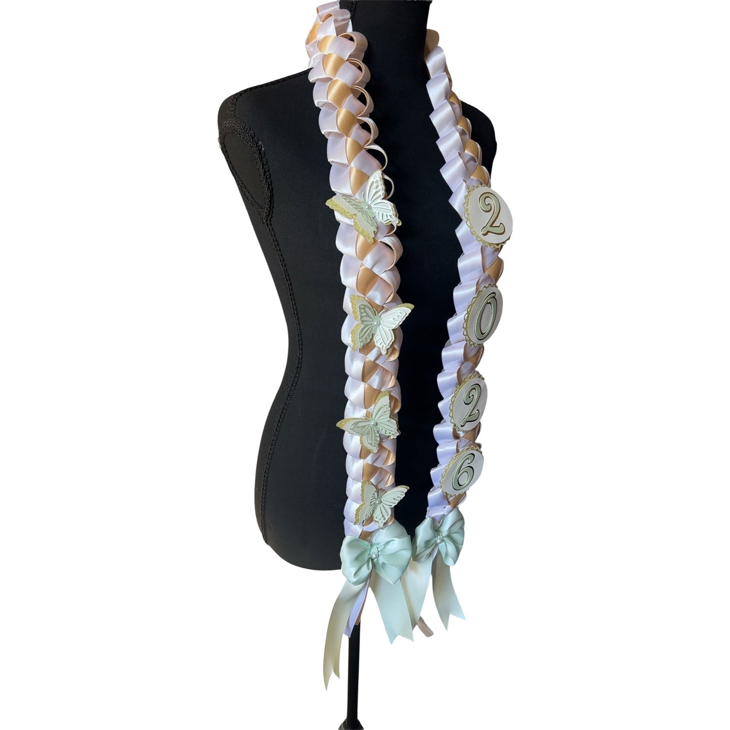 Side profile of a handcrafted ribbon graduation lei showing the intricate texture of the mint green and gold military braid and the detailed layered butterflies attached to the satin ribbon.