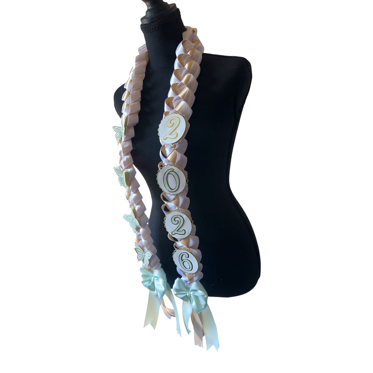 Angled view of a 2026 commemorative graduation lei highlighting the "2026" circular charms and the large mint green satin bows at the base of the white and gold military braid.