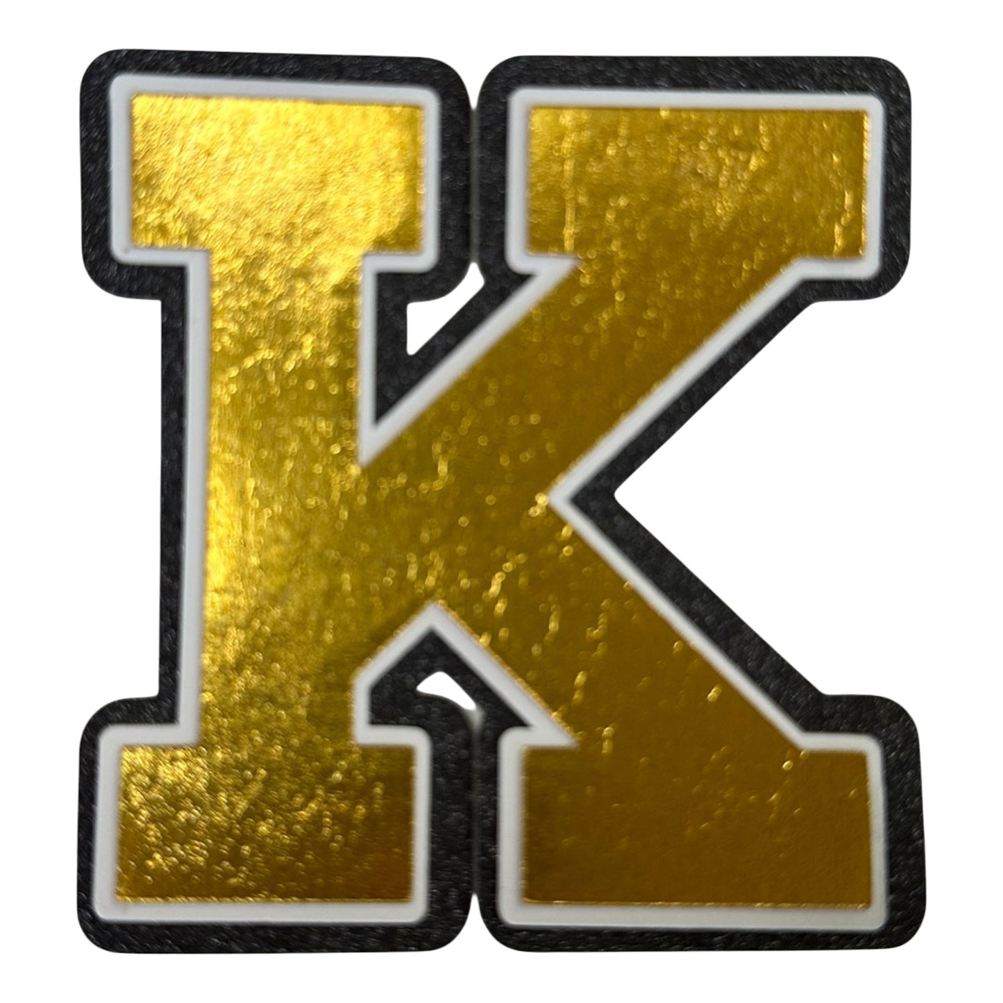 Black white and gold foil layered cardstock letter K cutout in varsity font for homecoming mums and graduation leis.