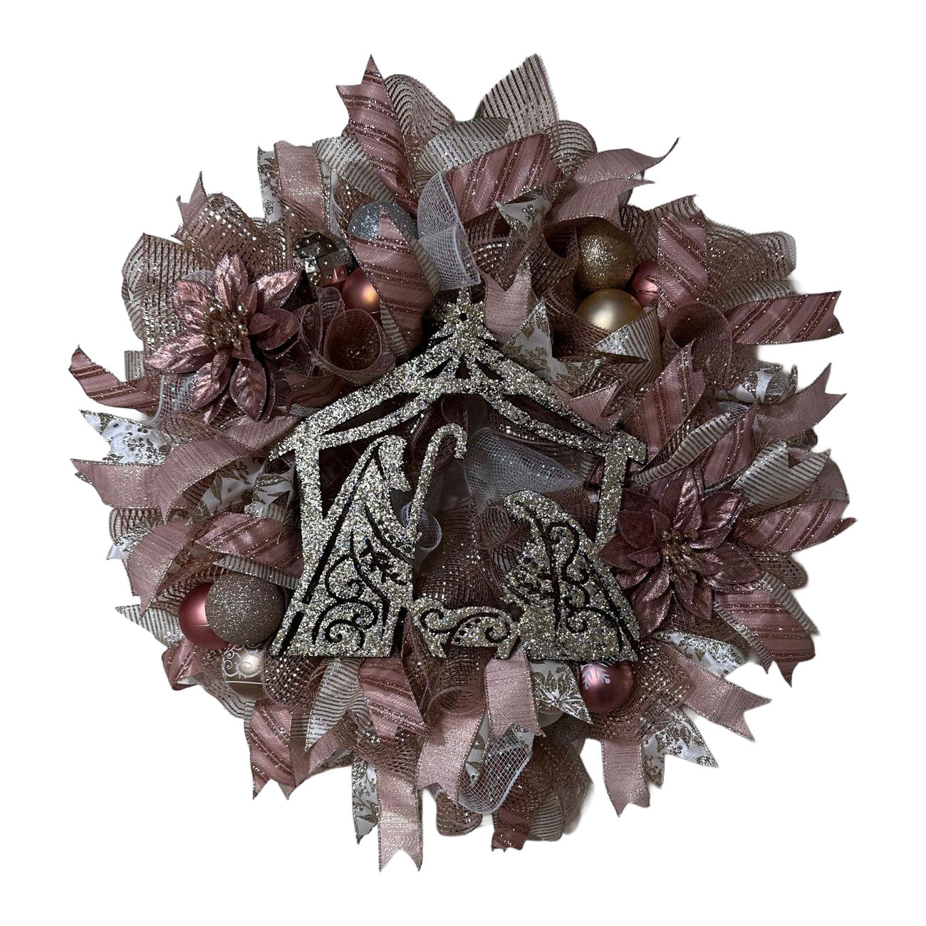 Decorative wreath with ribbons, ornaments, and rose gold nativity in the center on a white background.