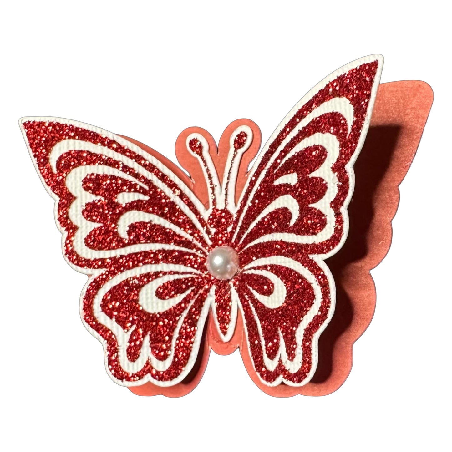 Detailed close-up of a 3D monarch butterfly cutout featuring intricate red glitter HTV patterns on white cardstock, layered over a solid red cardstock base with a central faux pearl.
