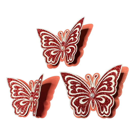 Set of three 3D monarch-style butterfly cutouts featuring layered red glitter HTV over white and red cardstock with faux pearl centers.