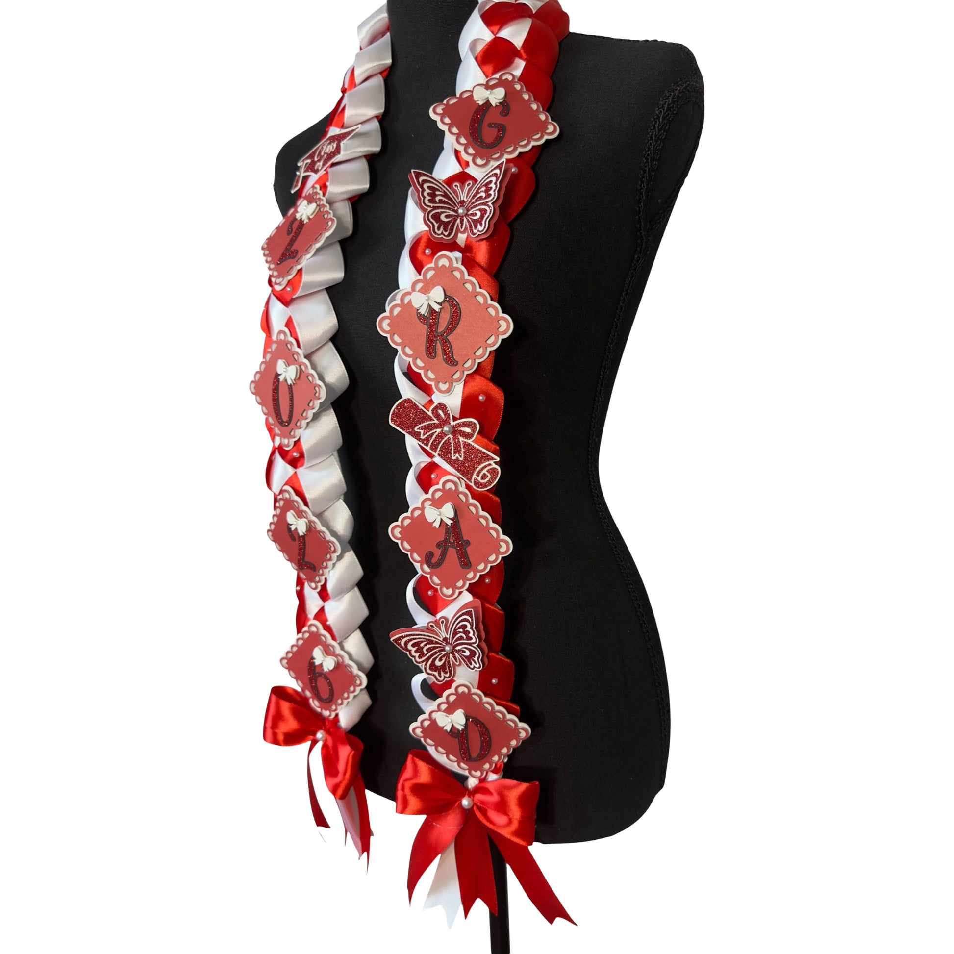 A three-quarter side view of a Red and White Single Military Braid Graduation Lei on a black mannequin torso, showcasing the left-side ribbon detail featuring the 'G', 'R', 'A', 'D' glitter scalloped charms and a red glitter diploma.
