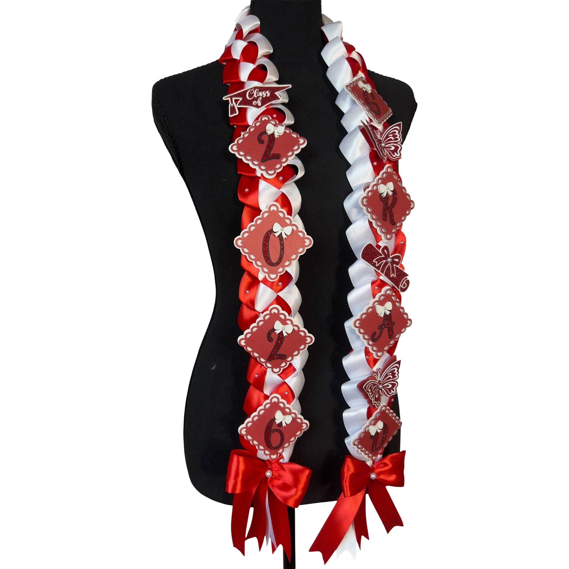 Close-up of a red and white military braid graduation lei featuring glittery red scalloped "GRAD" lettering, a white glitter "2026" charm, and delicate white bow accents with pearls.
